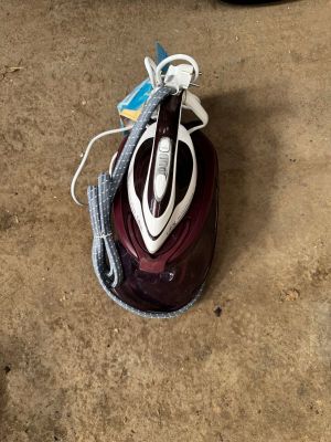 un fer à repasser posé par terre à côté d'un sac