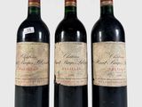 trois bouteilles de vin rouge posées l'une à côté de l'autre sur une surface blanche