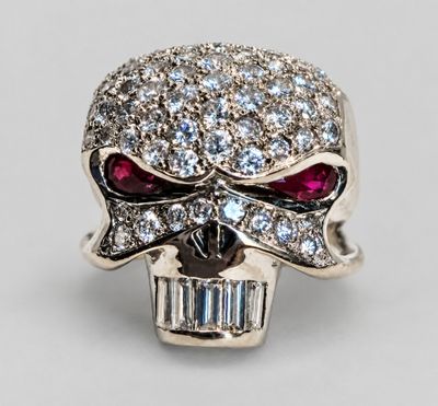 a close up of a skull ring with red eyes and a baguet