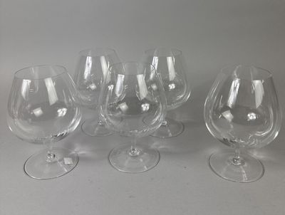 six empty wine glasses are lined up on a white surface