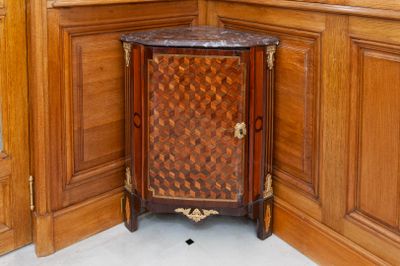 a corner cabinet with a marble top in a corner