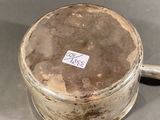 a small metal container with a handle on a table