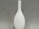 un vase blanc posé sur une table, sur fond gris