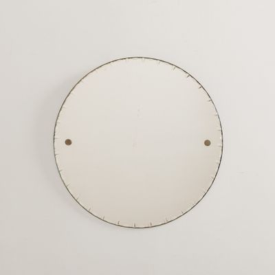un miroir rond blanc accroché au mur, à côté d'un mur blanc