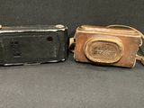 pair of antique cameras with leather case and tassel