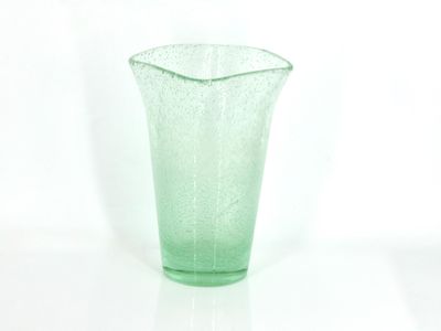 a green glass vase sitting on a white surface