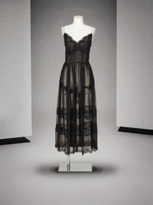 une robe noire posée sur un mannequin dans une pièce blanche