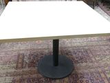 une table blanche avec un piètement noir dans une pièce