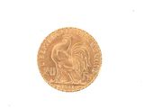 a gold coin with a rooster on it on a white surface