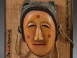 an image of a picture of a wooden mask hanging on a wall