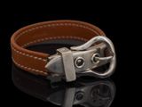 bracelet en cuir marron avec une boucle en argent sur un fond noir