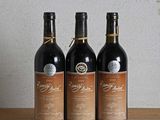 trois bouteilles de vin posées sur une table en bois, à côté d'une bouteille de vin