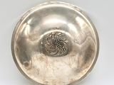 an antique silver plate with a flower in the center on a white background