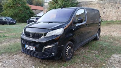 une petite camionnette noire garée sur la pelouse devant un immeuble
