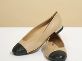 des chaussures beiges et noires posées sur une table blanche, sur fond beige
