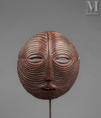 a wooden mask on a stand with a gray background
