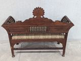 an old wooden bench with upholstered cushions and a decorative design