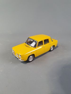 a yellow toy car that is sitting on a gray surface