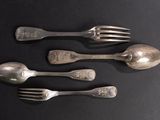 three silver spoons and two silver forks on a black surface