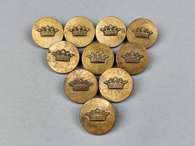 six boutons en laiton ornés de couronnes, posés sur une table
