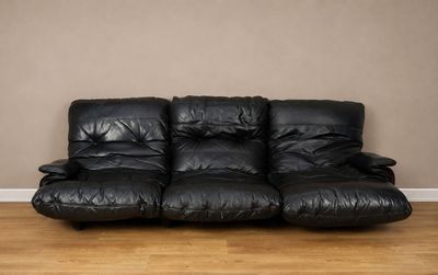 un canapé en cuir noir posé sur un parquet en bois massif