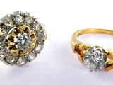 two gold rings with diamonds on them on a white surface