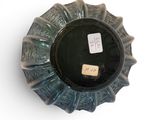a black vase with a label on it on a white surface