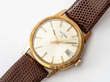 a close up of a watch on a white surface with a brown strap