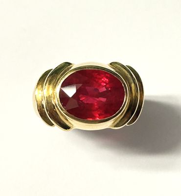 a close up of a ring with a red stone in it