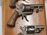two revolvers are mounted on a wooden plaque on a table