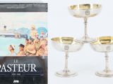 trois verres à vin plaqués argent et un livre sur fond blanc