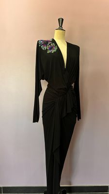 La robe est noire et est ornée de fleurs.