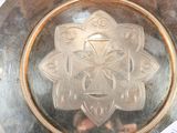 a silver plate with a design in the middle of it