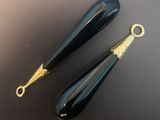 pair of black glass drop earrings with gold accents on a black surface