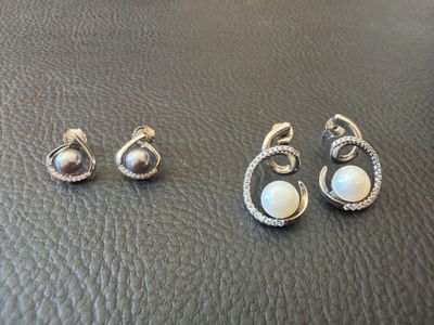 two pairs of earrings and a ring on a leather surface