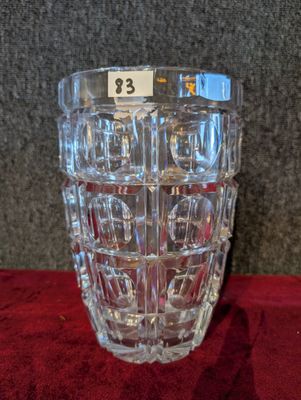 un vase en verre portant un numéro, posé sur un tissu rouge