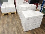 Plusieurs piles de cartons sont empilées sur une palette dans un entrepôt
