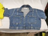 a blue jean jacket sitting on top of a white sheet
