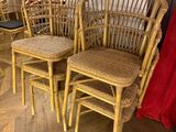 four wicker chairs and a table in a room with a red curtain