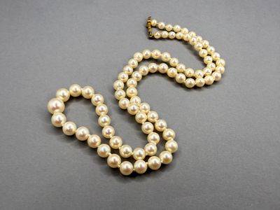a white pearl necklace with a gold clasp on a gray surface
