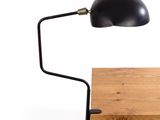 a black desk lamp on a wooden table with a white background