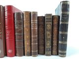 many old books lined up in a row on a white surface