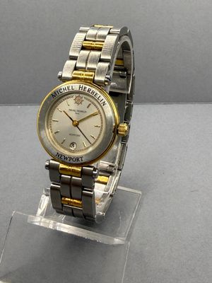 une montre en argent et en or posée sur un socle transparent