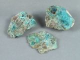 trois morceaux de roche de couleur turquoise posés sur une surface grise