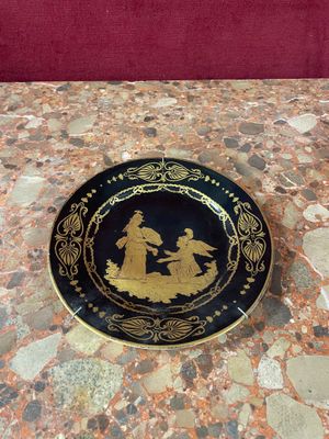 a black and gold plate with a picture of a man and a woman on it