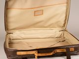 a brown suitcase that is open on a white surface