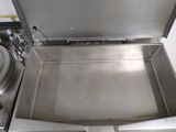 a stainless steel box with a lid open on a stove