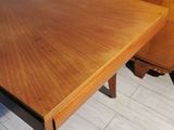 a wooden table with two chairs and a dresser in the background