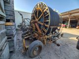 une grande bobine fixée à un chariot sur un chemin de terre