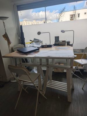 une table avec des chaises et un ordinateur portable posé dessus, dans une pièce